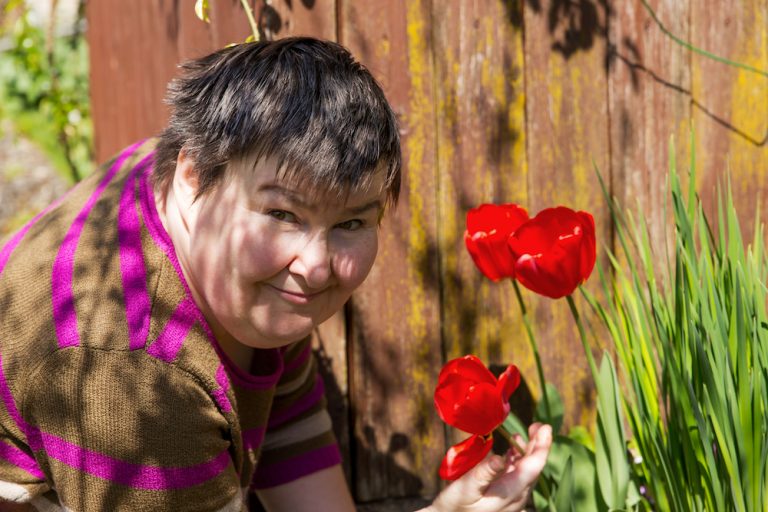 mentally disabled woman smells on a flower